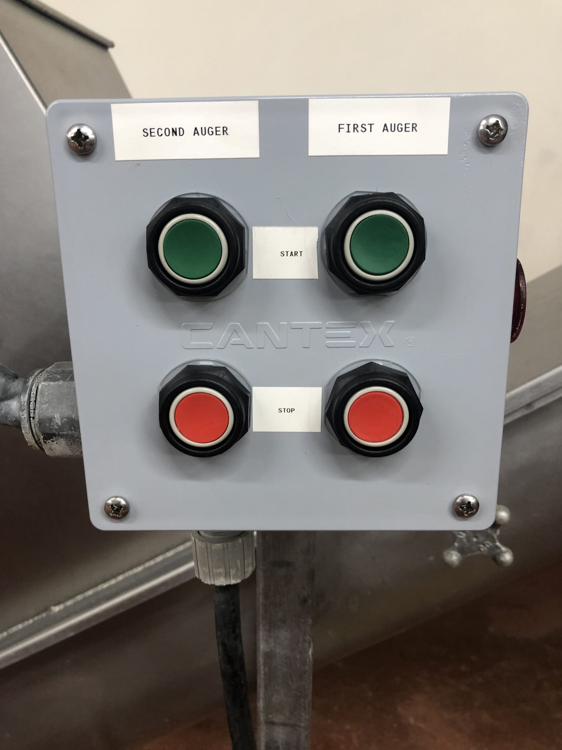 A control panel labeled “CANTEX” with four buttons: two green for “START” and two red for “STOP,” marked for “SECOND AUGER” and “FIRST AUGER.”.